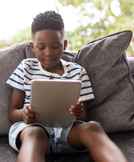 Boy sitting on sofa watching something on a tablet device